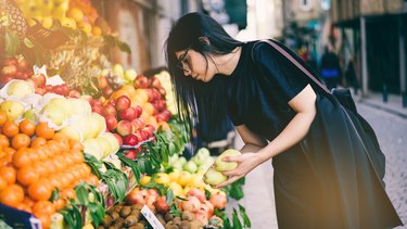 女人在街边市场买水果，以植物为基础的饮食预算