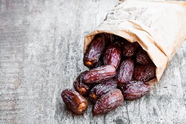 Dried  dates in paper bag on wooden table