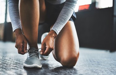 Women kneeling tying running sneakers