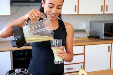 Woman pouring green smoothie into glass for protein shake recipes without protein powder