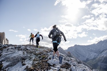 Trail running friends ascend mountain ridge