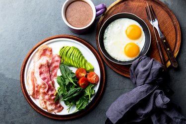 A keto diet breakfast with eggs, bacon, avocado and greens