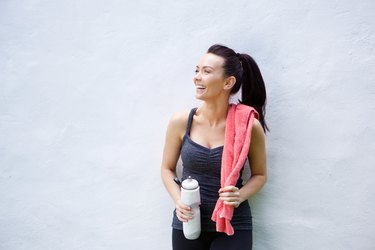 Smiling sporty woman with water bottle and towel
