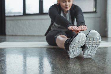 Overweight girl reaching her toes in gym