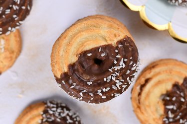 Round ring shaped sweet biscuits with half side glazed with chocolate and topped with coconut sprinkles