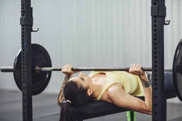 Woman doing bench press in gym