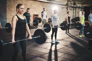 Group of adults holding heavy barbells in CrossFit class working legs