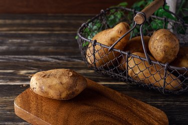 Raw unpeeled potatoes on wooden table