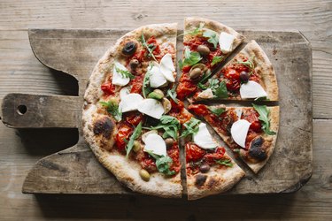 Sliced pizza on chopping board, overhead view