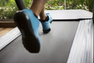 Man running on treadmill wearing blue sneakers getting cardio for weight loss
