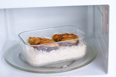 Container with food in the microwave. Rice and fish
