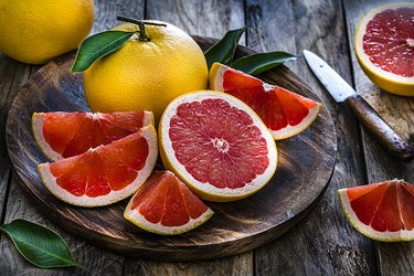 Whole and sliced grape fruit shot on rustic wooden table