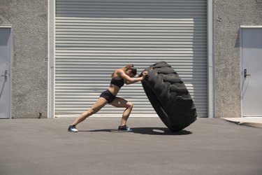 Young woman lifting a giant tire