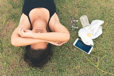 Exhausted athlete lying on the grass headache