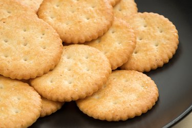 crackers cheese and crackers sugar in black plate on wood table