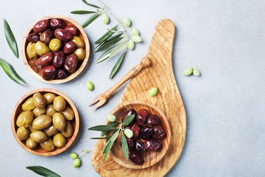 Natural greek olives in bowls with kitchen board from olive tree top view.