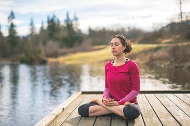 Young woman doing yoga outside by lake
