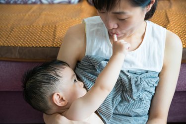 Asian mother breastfeeding and hugging her baby.