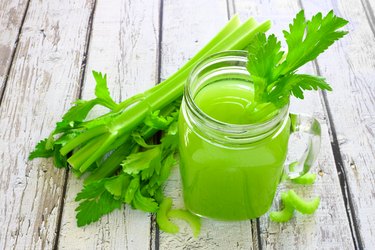 Celery juice in a mason jar against a white wood background