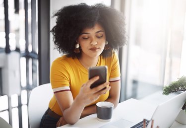 Woman reading nutrition or weight-loss articles on smartphone with laptop