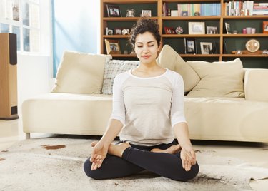 Woman relaxing in yoga pose in livingroom.