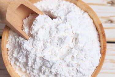 Close-Up Of Flour With Serving Scoop In Wooden Bowl On Table