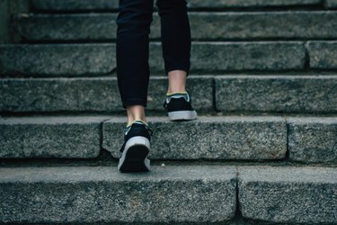 The girl in black jeans climbs on concrete stairs