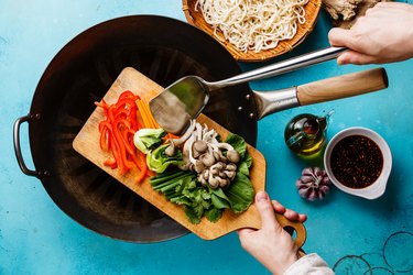 Cooking vegetables to preserve nutrients in a frying pan, cutting board with mushrooms peppers and spinach.