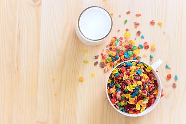 Kids healthy quick breakfast. Colorful rice cereal with milk on wooden background. Copy space