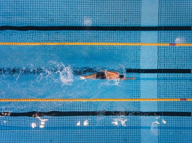 Young man swimming laps in a pool for health benefits