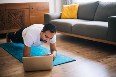 Man uses laptop to lean plank position