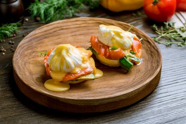 eggs Benedict with salmon and avocado on a wooden board
