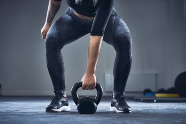 Close-up of athletic woman exercising with kettlebell at gym