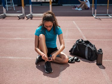 Latina athletic woman tying her shoes before running