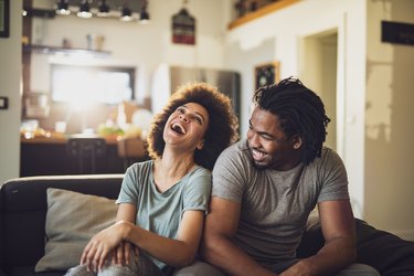 Young cheerful African American couple in the living room.