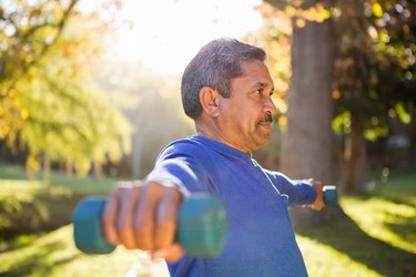 Man exercising with dumbbell on sunny day