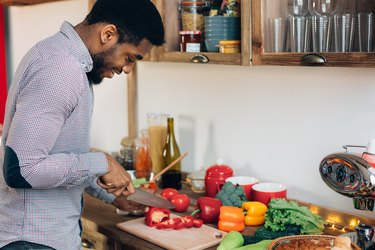 Black man cutting bell pepper in kitchen