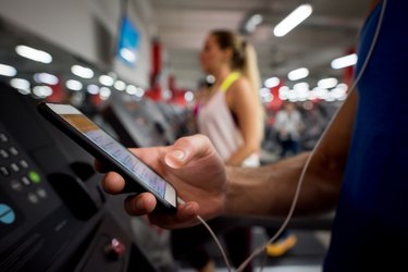A man using his smartphone on the treadmill