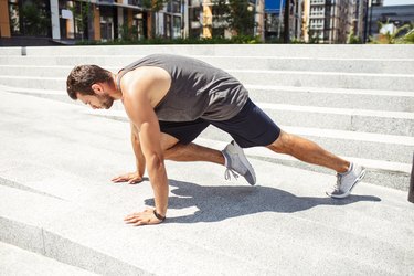 年轻人在外面锻炼。Athletist做登山运动员训练。在城市建筑锻炼独自在水平位置。强大的athletist强劲。