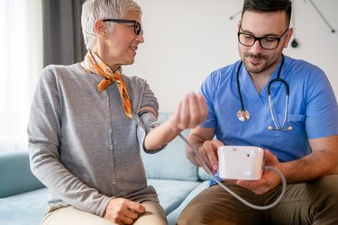 doctor measuring older woman's blood pressure