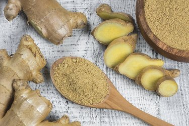 Fresh chopped ginger root and ground ginger powder in wooden spoon on wooden rustic table. Healthy food spice concept. Zingiber officinale