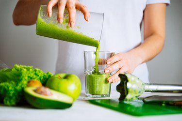 woman pouring green smoothie into glass