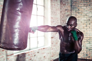 Black boxer punching the heavy bag in the gym