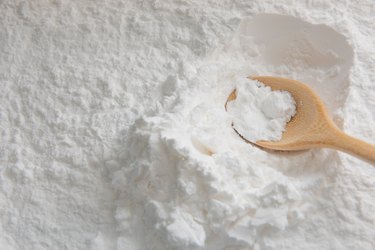 Close-up of tapioca starch or flour powder in wooden spoon with wooden background