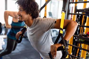 Man training with trx fitness straps in the gym. Workout healthy lifestyle sport concept