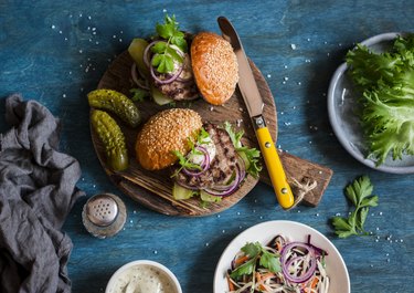 Two homemade burgers on a wooden cutting board