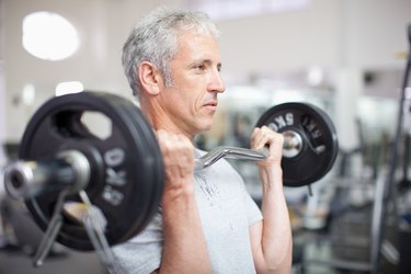 Portrait of smiling man holding barbell in gymnasium