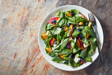 healthy salad with fresh chard leaves, peach, blueberries, pieces of cheese