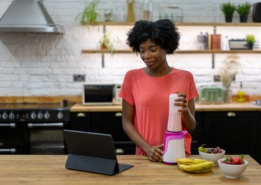 Woman making a smoothie at home following an online recipe