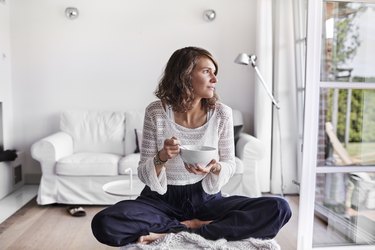 Young woman sitting in living room having breakfast